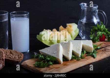 Türkisches Raki mit Wasser auf dem Tisch mit Melonenscheiben und Vorspeise, traditioneller türkischer Alkohol, bekannt als Raki, Chill mit Freunden im Restaurant, Abendessen Stockfoto