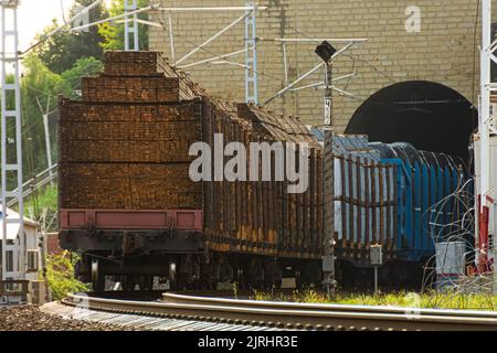 Verarbeitete Spanplatten werden auf Güterwagen verladen und per Zug in bergigen Gebieten durch einen Tunnel zu ihrem Ziel geschickt Stockfoto