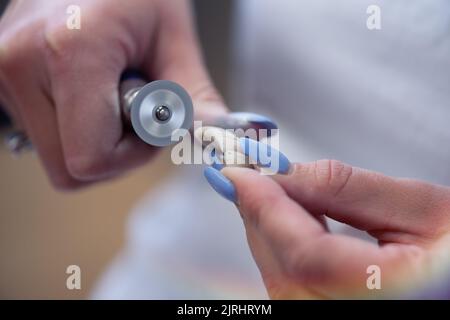 Prothetik Hände während der Arbeit an der Prothese, falsche Zähne, eine Studie und einen Tisch mit zahnmedizinischen Werkzeugen. Stockfoto