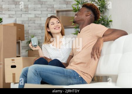 Glückliches Paar, das sich auf dem Sofa entspannt und Spaß am Tag des Umziehens hat Stockfoto