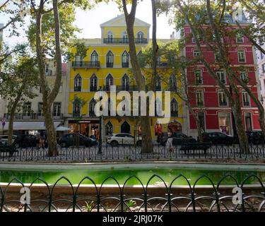 Gelb-rote Gebäude an der Avenida da Liberdade (Liberty Avenue), einem Boulevard im Zentrum von Lissabon, Portugal, mit seinen teuersten Gebäuden. Stockfoto