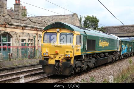 Freightliner Klasse 66, 66606, durch Carnforth auf der West Coast Main Line 24.. August 2022 mit Güterzug, Waggons mit Graffiti. Stockfoto