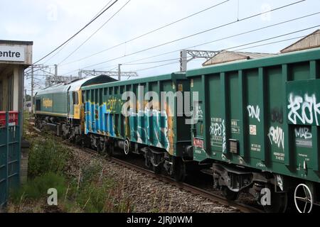 Freightliner Klasse 66, 66606, durch Carnforth auf der West Coast Main Line 24.. August 2022 mit Güterzug, Waggons mit Graffiti. Stockfoto