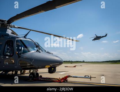 Ein MH-139A Grey Wolf sitzt auf der Fluglinie, während ein anderer am 17. August auf der Eglin Air Force Base, Florida fliegt. Der ausgestellte Grey Wolf Flug war der erste Flug seit der Übernahme des Flugzeugs durch die Air Force am 12. August. Es war auch der erste All-Air-Force-Personalflug im neuesten Hubschrauber der Air Force. (USA Luftwaffe Foto/Samuel King Jr.) Stockfoto