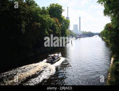 Berlin, Deutschland. 24. August 2022. Ein Boot fährt auf dem Teltow-Kanal in Berlin Lichterfelde in Richtung Kraftwerk Lichterfelde. Das Kraftwerk wird von der Vattenfall Wärme Berlin AG mit Erdgas betrieben und produziert Strom und Fernwärme für den Süden Berlins. Quelle: XAMAX/dpa/Alamy Live News Stockfoto