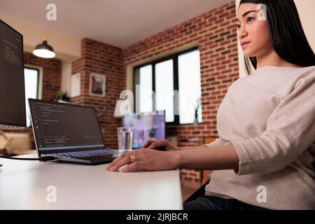 Freelance asiatische Software-App-Entwickler mit Terminal-Fenster zu Hause, Programmierung Sicherheits-Firewall, mit css HTML-Skript. Programmierer Entwicklung neuer Benutzeroberfläche Online-App Cloud-Server. Stockfoto