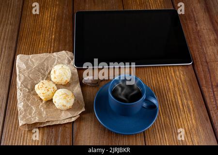 Brasilianisches Käsebrot neben Kaffeetasse, Kupferlöffel und Tablette. Stockfoto