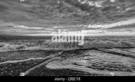 Eine Ozeanwelle Bricht Mit Wolken Über Schwarz Und Weiß Stockfoto