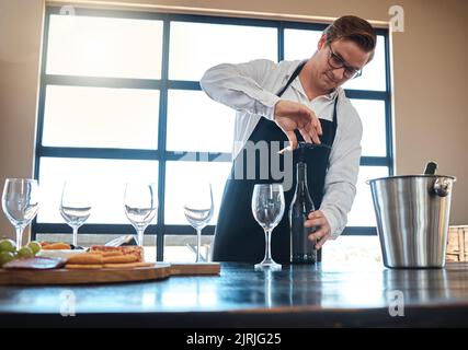 Barkeeper mit Rotwein-Verkostung in einem Luxusrestaurant oder Weingut und Vintage-Alkoholflasche und Gläsern für feines Essen, Kulinarik oder Gastfreundschaft Stockfoto