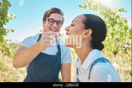 Liebe, Landwirtschaft und Paar auf einem Weinberg in glücklichen Moment teilen Trauben auf einer Weinprobe Bauernhof. Mann und Frau zusammen mit süßen Spaß, während Stockfoto