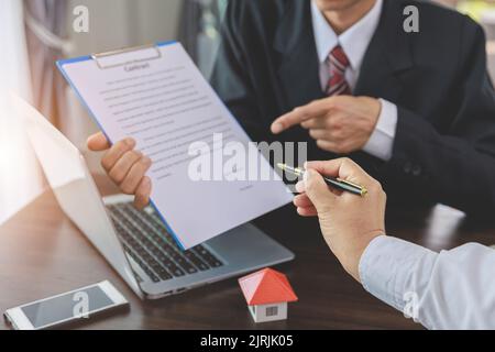 Hand des Maklers, der dem Kunden zeigt, wo er einen Unterschriftsvertrag, ein neues Zuhause und Immobilienhandelskonzepte unterzeichnet. Stockfoto