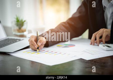 Der Geschäftsmann arbeitet an Statistiken und Geschäftsgraphen, der Geschäftsmann mit einem Stift arbeitet mit Diagrammdokumenten, Börsendiagrammen. Stockfoto