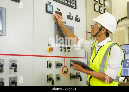 Ingenieur, der an der Schaltanlage zur Überprüfung des Status der elektrischen Energieverteilung arbeitet. Informationen zur Elektriker- und Werkzeugprotokollierung in elektrischen en Stockfoto