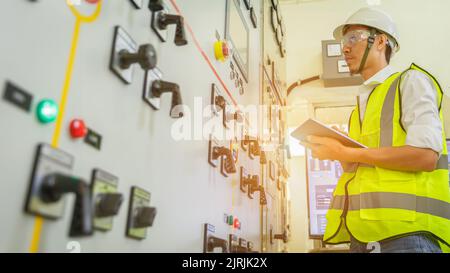 Erfahrener Elektriker, der in der Schaltwarte des Kraftwerks arbeitet. Ingenieur, der am Unterstat zur Überprüfung des Status der elektrischen Energieverteilung der Schaltanlage arbeitet Stockfoto