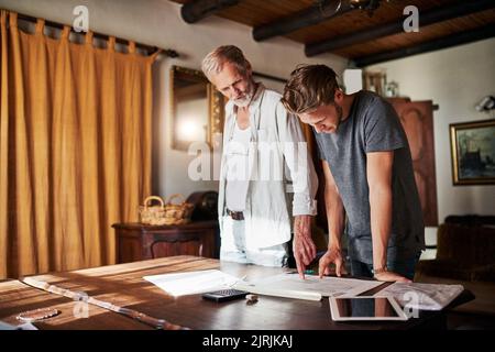 Sie teilen die Leidenschaft für den Bau von Träumen. Zwei Männer arbeiten zu Hause an einem Projekt zusammen. Stockfoto