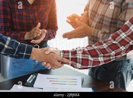 Junge Geschäftsleute geben sich die Hände. Abschluss eines erfolgreichen Meetings. Teamarbeit. Stockfoto
