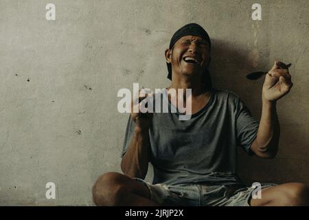 Drogenabhängiger Mann mit Halluzinationen, drogenabhängiger Mann mit Spritze, der Drogen verwendet. Stockfoto