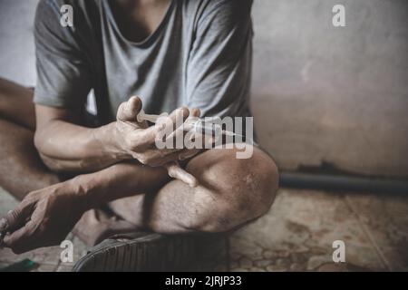 Drogenabhängiger Mann, der Heroin in seinen Arm injiziert, Drogenabhängiger Mann mit Spritze, Drogen-Konzept, 26. Juni, Internationaler Tag gegen Drogenmissbrauch Stockfoto