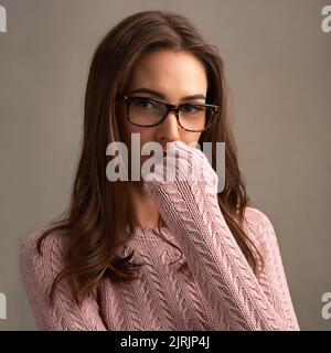 Selbst zu sein ist das, was dich schön macht. Eine schöne junge Frau posiert vor einem braunen Hintergrund. Stockfoto