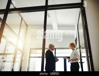 Auf der Suche nach Rat von ihrem Mentor. Zwei Geschäftsleute, die im Büro stehen, sprechen. Stockfoto