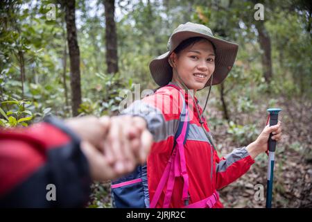 Junges Paar auf Wandertour. Junger Mann und Frau Wanderer halten sich die Hände, während sie auf dem Bergweg wandern. Stockfoto