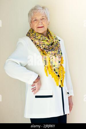 Immer noch stylin mit 70. Porträt einer gut gekleideten älteren Frau, die selbstbewusst mit der Hand auf der Hüfte posiert. Stockfoto