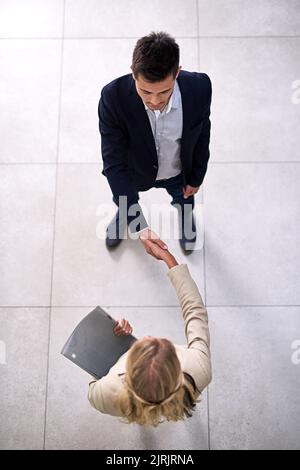 Herzlichen Glückwunsch, du bist eingestellt. Aufnahme von zwei professionellen Geschäftsleuten, die sich im Büro die Hände schüttelten. Stockfoto