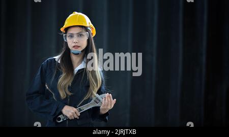 Porträt eines schönen asiatischen Ingenieurs mit einem Schraubenschlüssel der Hintergrund ist ein Container, ein Konzept eines Ingenieurs oder eines Industriemechanikers. Stockfoto