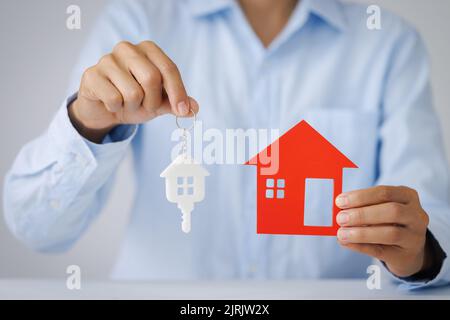 Hände, die ein Hausmodell halten. Immobilienwirtschaft Hypothekenplan und Wohnsteuer-Sparstrategie, Hypothek, Investitionen, Immobilien und Immobilien conce Stockfoto