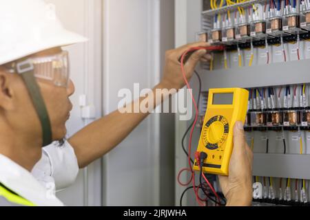 Elektriker Ingenieur Arbeitstester zur Messung der Spannung und des Stroms der elektrischen Stromleitung in der elektrischen Schaltschranksteuerung. Stockfoto