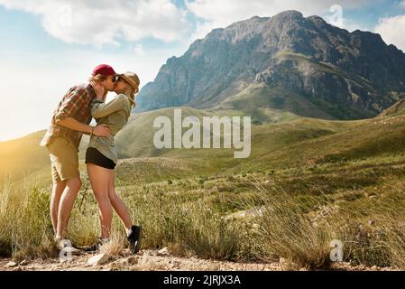 Ein liebevolles junges Paar, das einen Kuss in der Natur teilt. Stockfoto