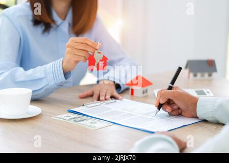 Home Sales und Home Insurance Konzept. Immobilienmakler sprach über die Bedingungen des Hauskaufvertrags und bat den Kunden, das Dokument zu unterzeichnen Stockfoto