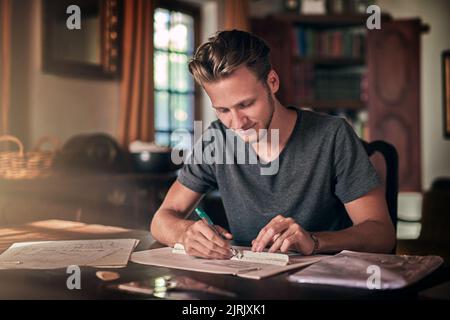 HES fleißig über seine Hausaufgaben. Ein fleißiger junger Student, der eine Hausaufgabe zu Hause macht. Stockfoto