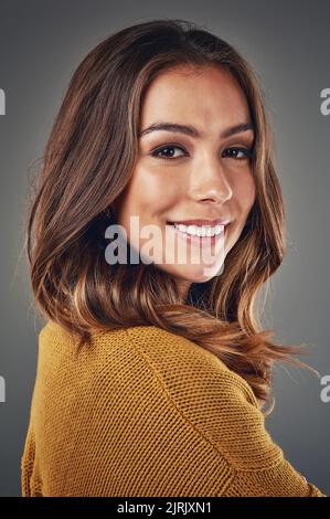 Erleben Sie Schönheit hautnah und persönlich. Studioportrait einer attraktiven jungen Frau, die vor grauem Hintergrund posiert. Stockfoto