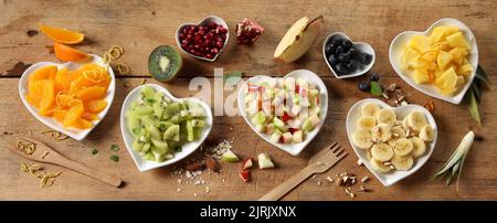 Fruchtige Herzen. Frisches Obst auf Tellern auf rustikalem Holztisch. Draufsicht, Kopierbereich. Sortiment verschiedener Früchte auf Holztisch. Stockfoto
