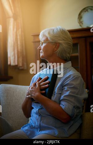 Setzen Sie Ihre Hoffnung in sein Wort. Eine ältere Frau hält eine Bibel zu Hause. Stockfoto