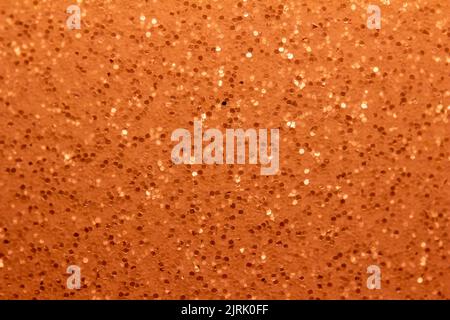 Abstrakte Vollformatstruktur mit schimmerndem orangefarbenem Glitzer-Hintergrund und selektivem Fokus Stockfoto