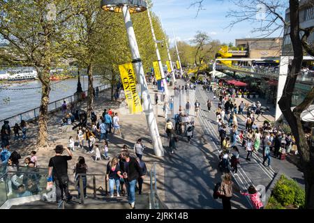 South Bank, London, Großbritannien. 15.. April 2022. Erhöhter Blick auf Londons South Bank Promenade, die von Menschen belebt ist, die die lokale Atmosphäre genießen. Stockfoto