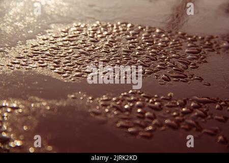 Abstraktes Makro von Wassertropfen auf braunem Hintergrund. Stockfoto