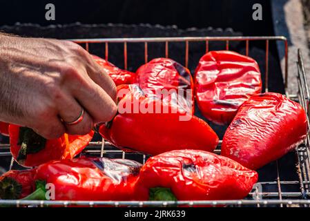 Grillen Prozess der Vorbereitung roten Paprika auf Grill bbq Grill. Flammendes Feuer, Kohle und Rauch. Nahaufnahme der ganzen Straße Food Picknick vegetab Stockfoto