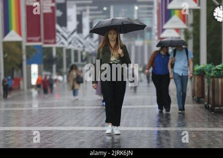 Die Menschen laufen im Regen den Wembley Way entlang, im Nordwesten Londons, da das Met Office eine gelbe Warnung für Gewitter und heftigen Regen in Süd- und Ostengland ausgegeben hat, wobei die Fahrbedingungen möglicherweise durch Spray, stehendes Wasser und sogar Hagel sowie mögliche Verzögerungen bei den Zugdiensten beeinträchtigt werden, Stromausfälle, Überschwemmungen und Blitzeinschläge. Bilddatum: Donnerstag, 25. August 2022. Stockfoto