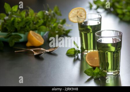 Zitrone Minze Eistee grünen Tee Cocktail erfrischende Getränk für Sommertage zwei Glas Kräuter dunklen Hintergrund Stockfoto