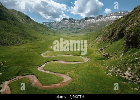 Von oben grünes grasbewachsenes Tal mit gewundenen Pfaden zwischen Berghängen, die sich gegen raue felsige Klippen in der Natur Spaniens in den Pyrenäen befinden Stockfoto