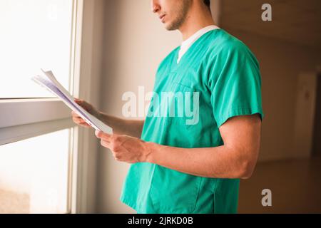 Ernte anonymen männlichen medizinischen Befund in der Nähe Fenster in Krankenhaus Passage Stockfoto