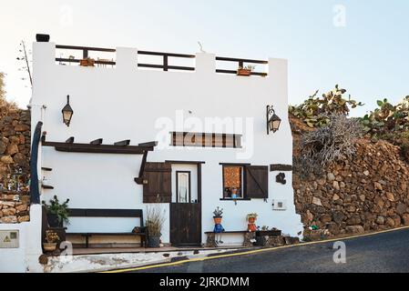 Wohngebäude außen mit weißer Stirnwand und offenen Fensterläden gegen Asphaltstraße in Fuerteventura auf den Kanarischen Inseln Spanien Stockfoto