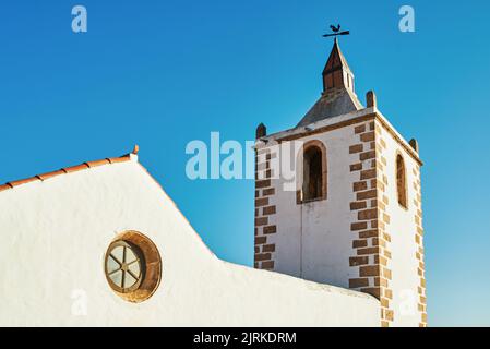 Gealterte klassische Kirche campanile Fassade in Fuerteventura Spanien unter blauem Himmel Stockfoto