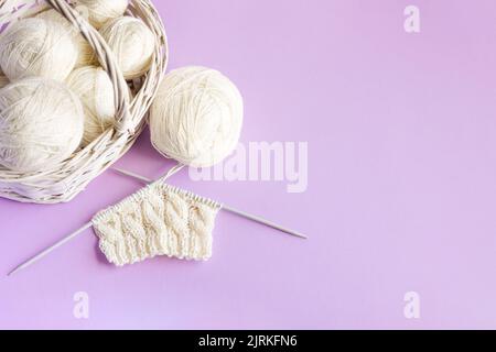 Weiße Kugeln aus Faden in einem Korb auf einem rosa Hintergrund, Hobby Stockfoto