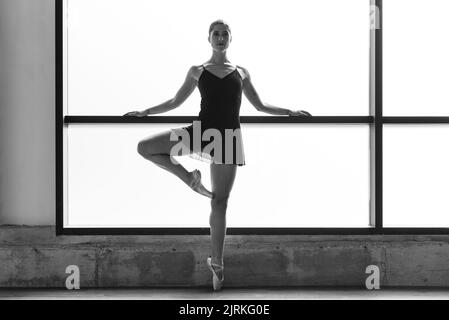 Foto der jungen Ballerina, die im Tanzstudio auf Zehenspitzen posiert Stockfoto