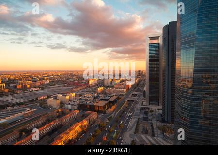 Von oben des modernen Viertels von Madrid mit Wolkenkratzern in Abendsonne unter schönem Himmel mit Wolken Stockfoto
