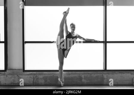 Foto der jungen Ballerina, die im Tanzstudio auf Zehenspitzen posiert Stockfoto